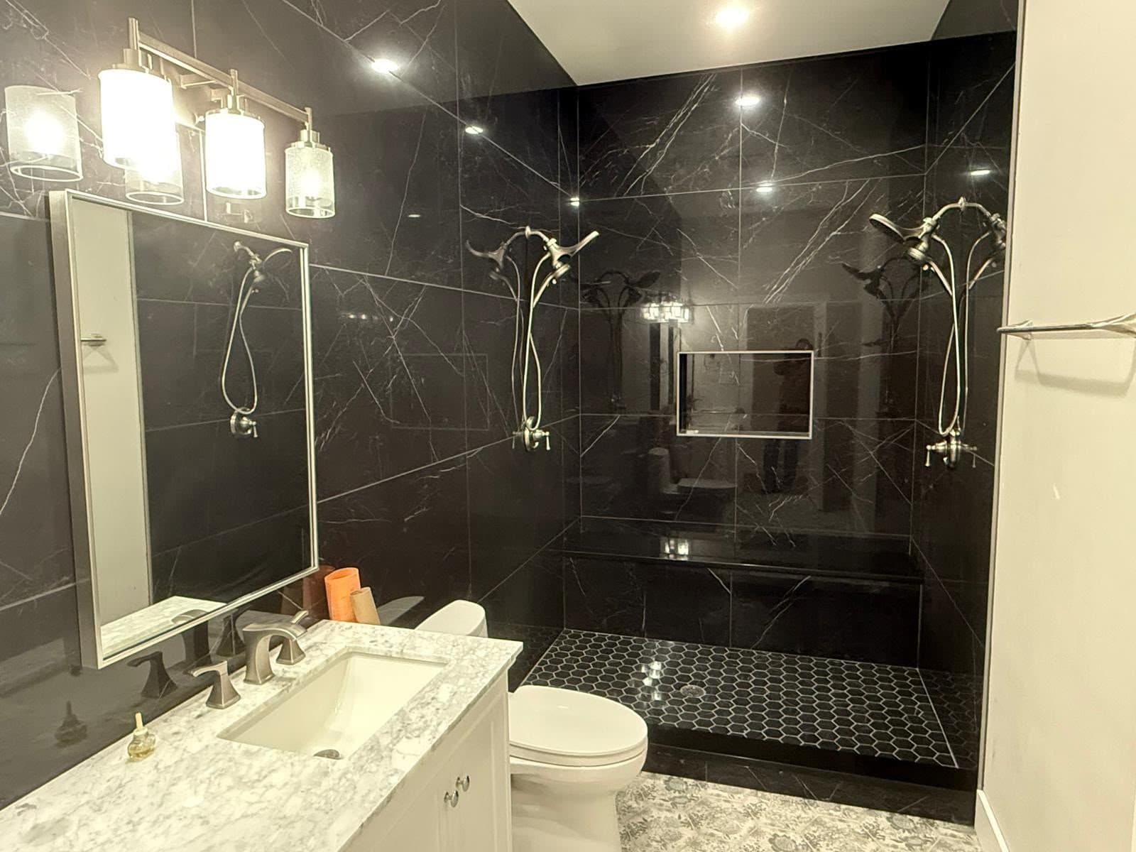 A finished Rhino Renovations bathroom with dark marble tile and a glass shower.